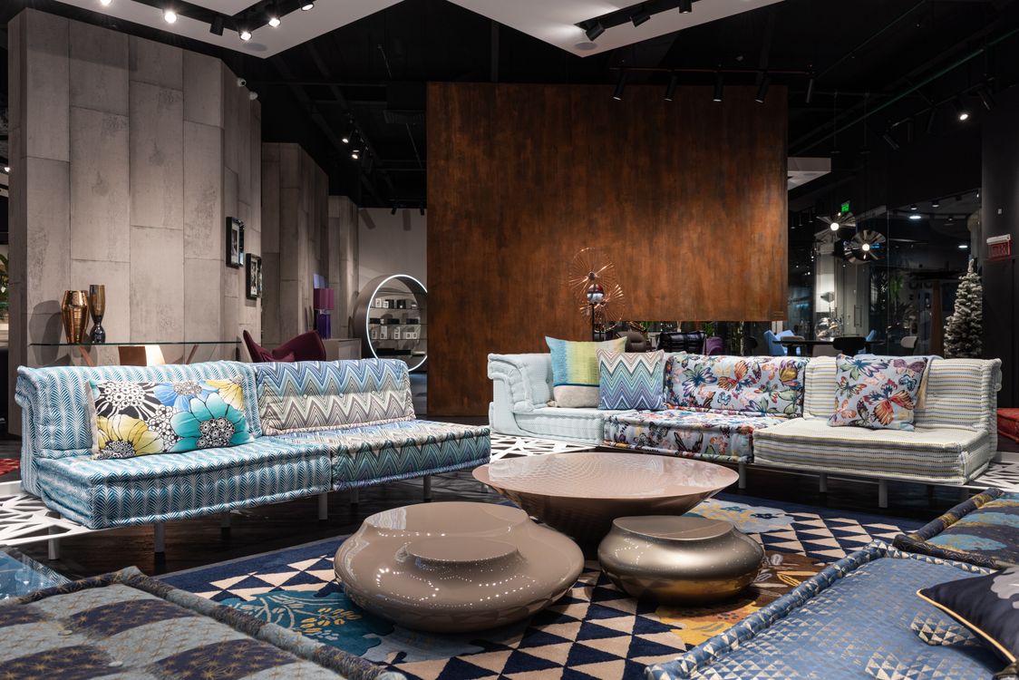 Free Comfortable sofas with colorful cushions and creative coffee tables placed on carpet in modern spacious furniture store Stock Photo