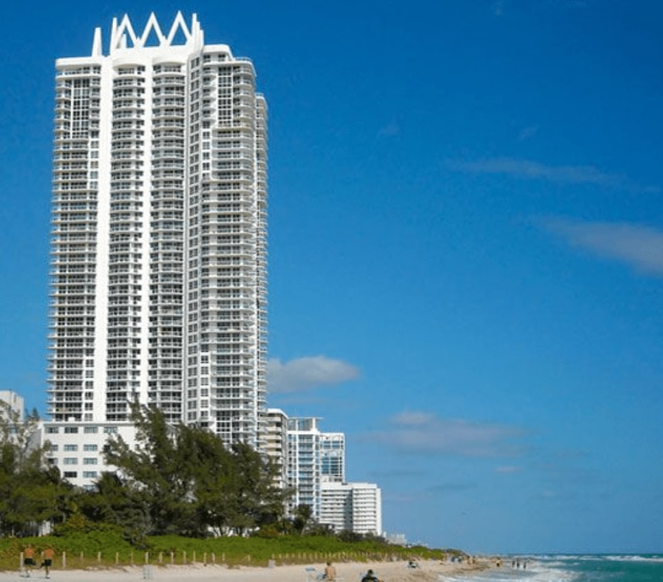 A white oceanfront condominium tower above the beach