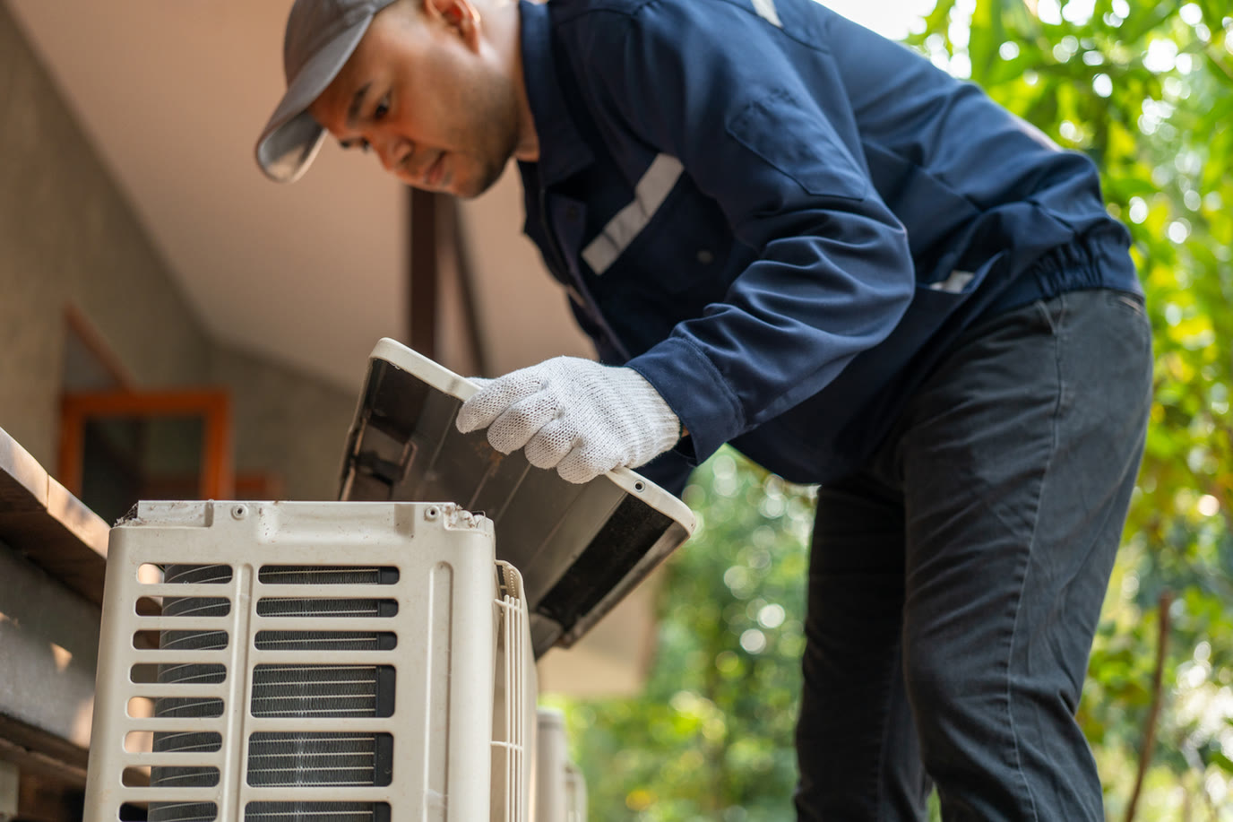 HVAC technician opening an outdoor condenser cover during a seasonal maintenance visit