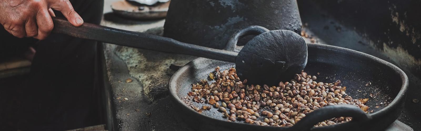 Coffee beans roasting in a clay pan