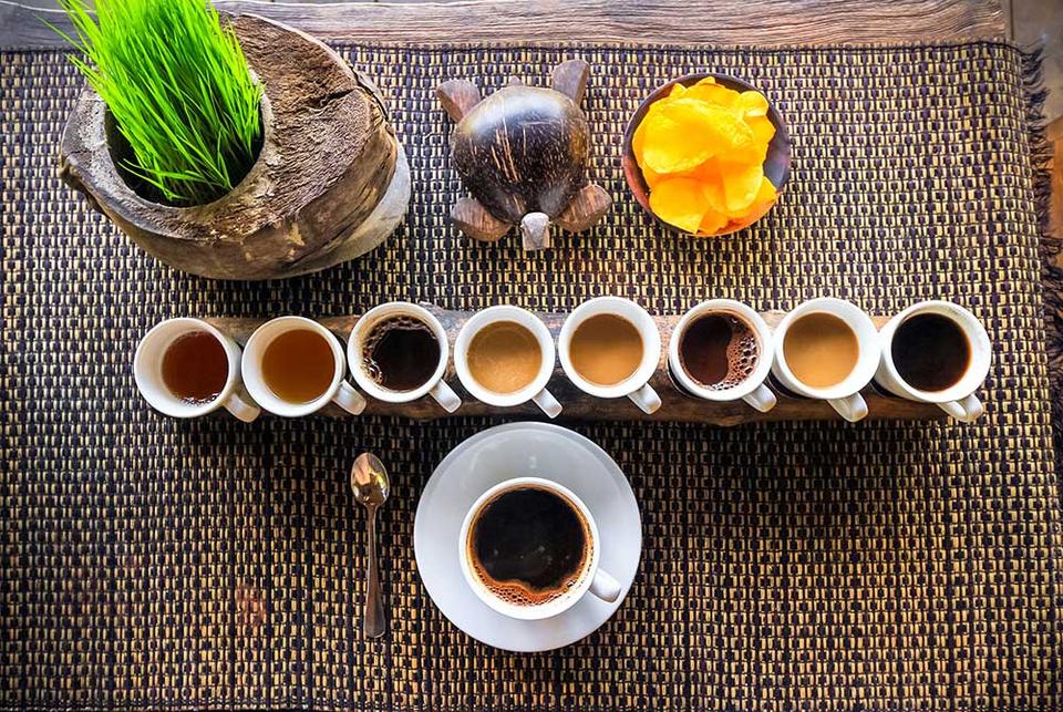 A flight of Bali coffee cups on a woven mat with fresh fruit