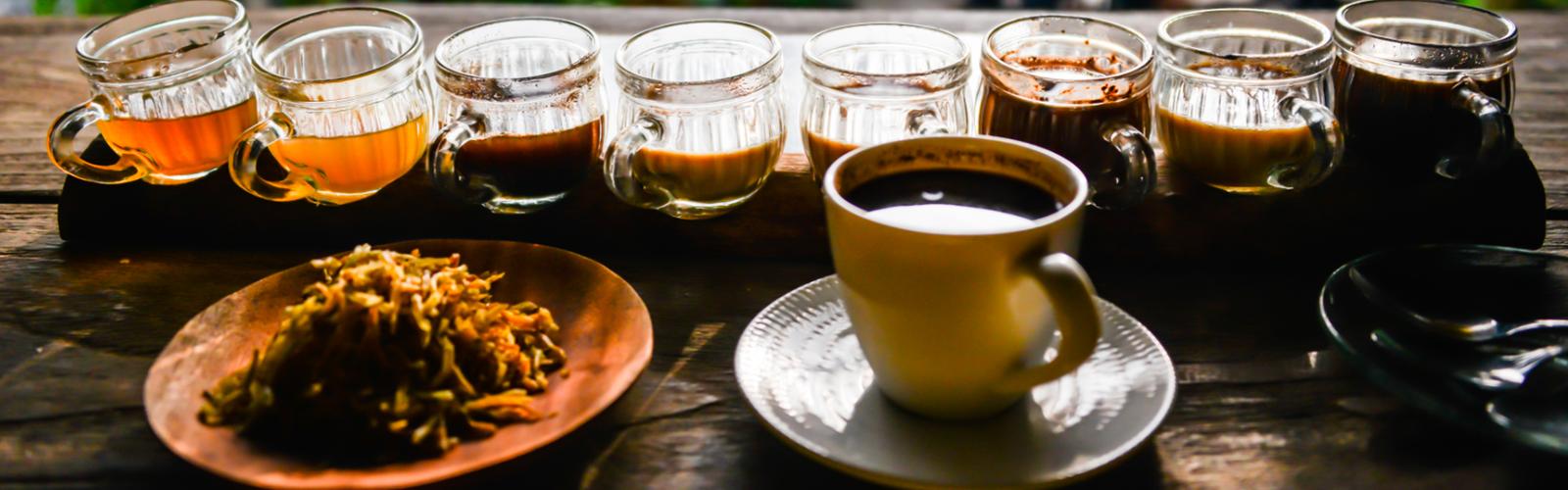 Balinese coffee served in a yellow cup beside a tasting flight on a wooden table