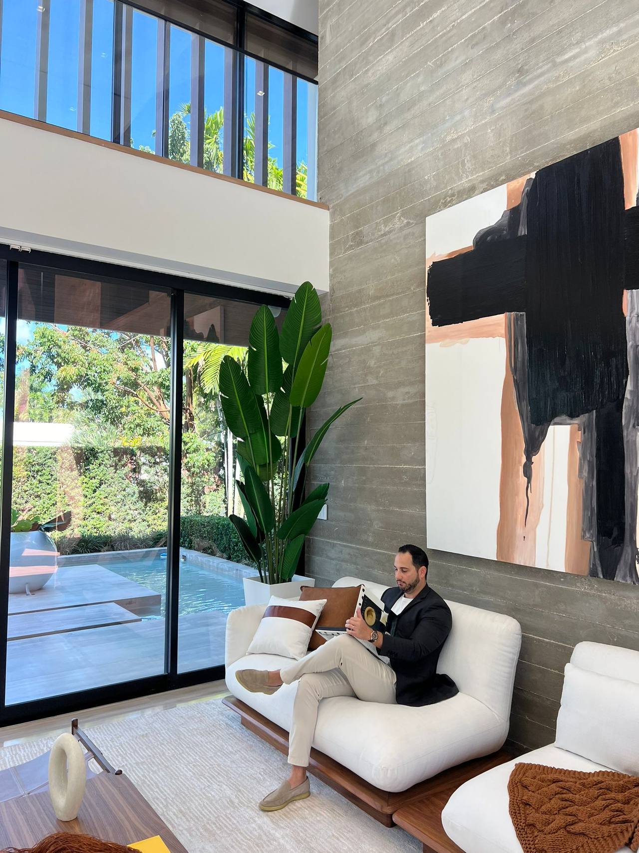 Jonathan Bigelman seated in a double-height Miami living room overlooking the pool