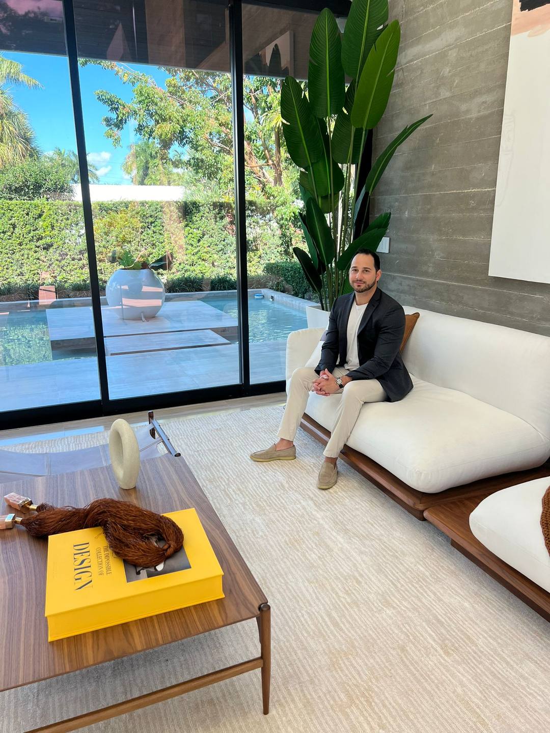Jonathan Bigelman seated in a Miami living room opening onto a pool terrace