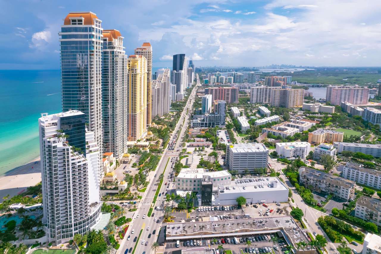 Aerial view of a dense wall of oceanfront condominium towers along the beach