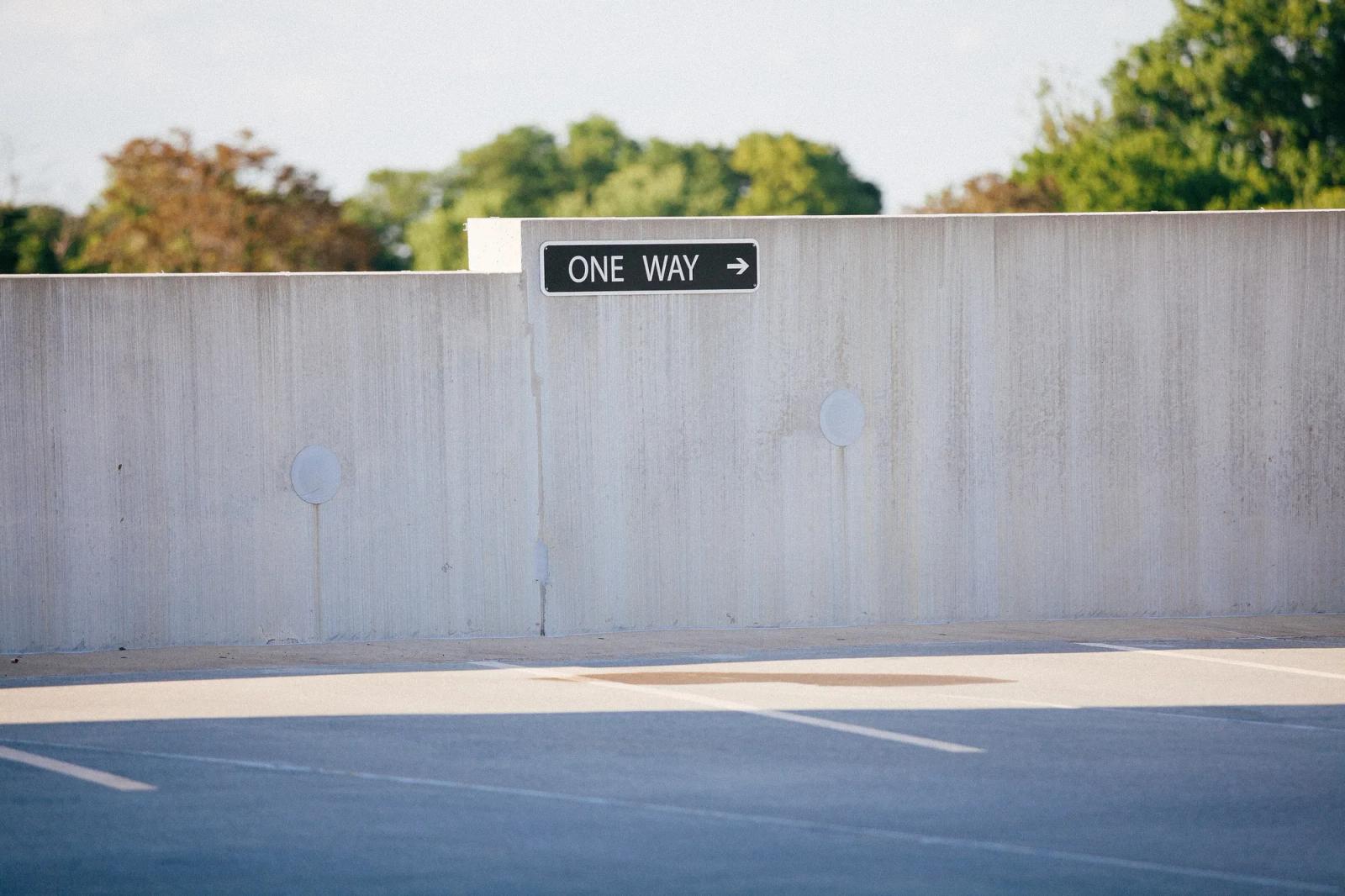 A one-way sign on a concrete wall